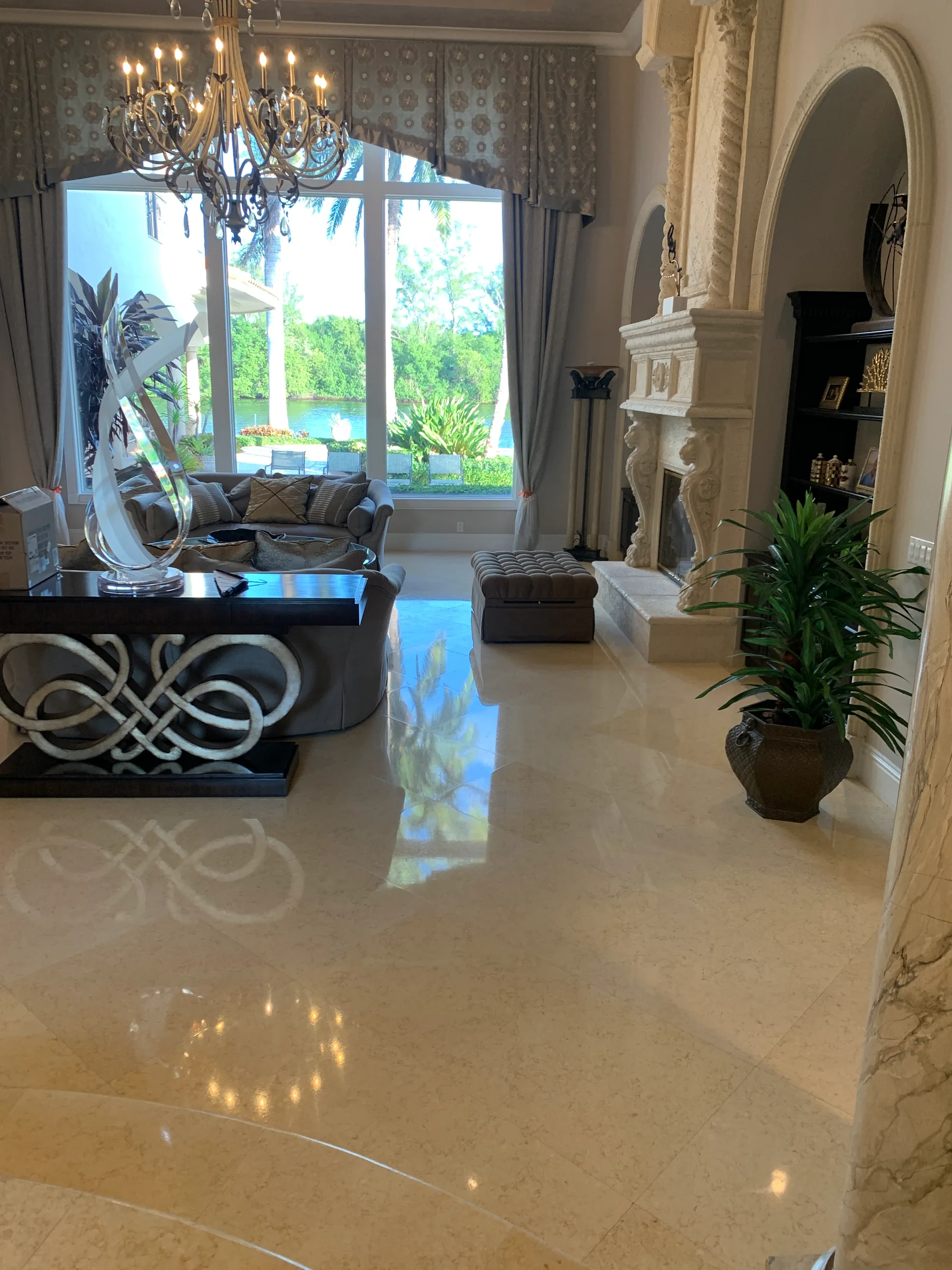 Polished marble floor in luxury living room with waterfront view and chandelier.
